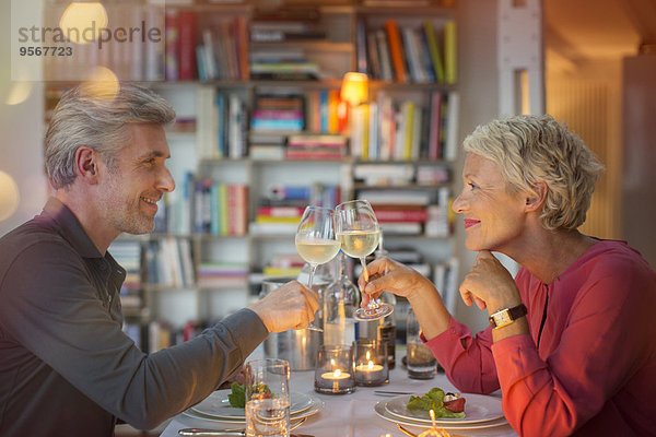 Ältere Paare stoßen sich beim romantischen Abendessen an.