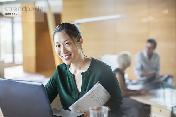 Geschäftsfrau lächelt mit Laptop im Büro