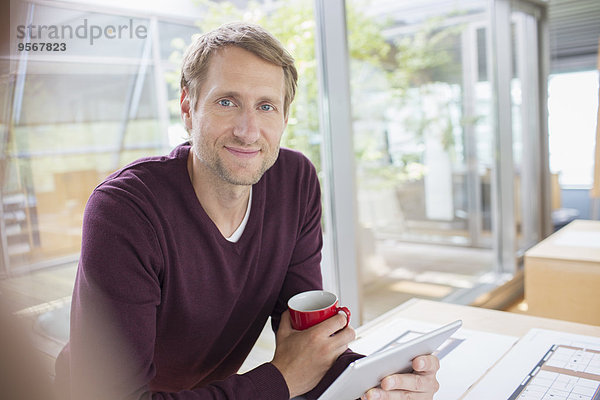 Geschäftsmann mit digitalem Tablett am Schreibtisch