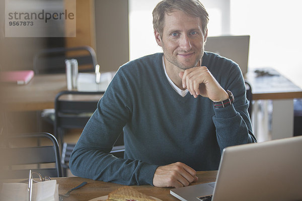 Geschäftsmann mit Laptop in der Cafeteria