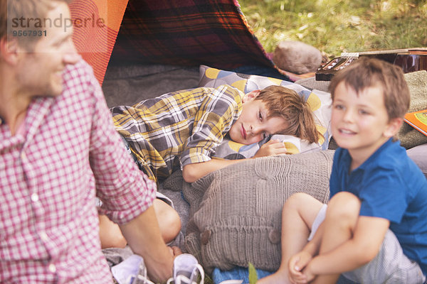 Vater und Söhne lächeln auf dem Campingzelt