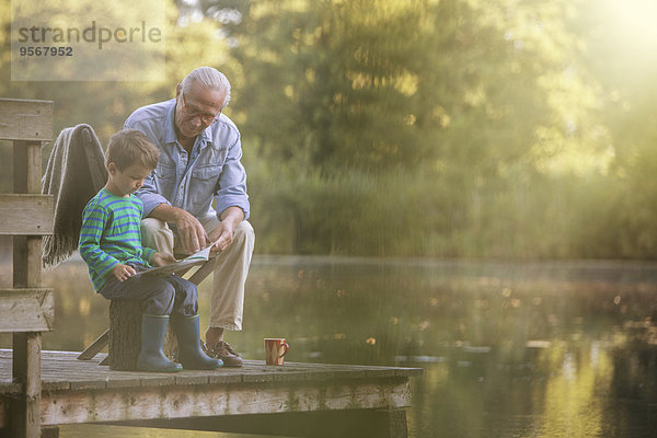 Großvater und Enkel lesen am See