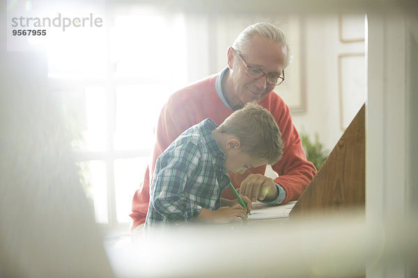 Großvater und Enkel schreiben am Schreibtisch