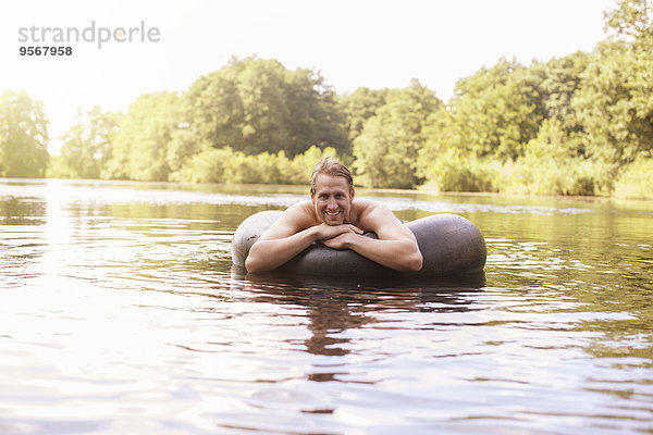 Mann schwimmt im Innenrohr im See