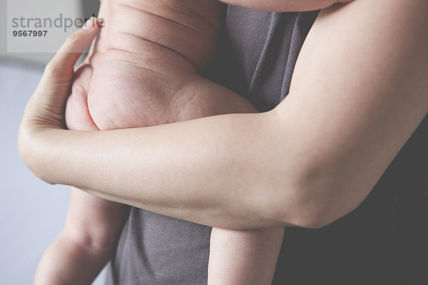 Blick auf die Hände der Mutter mit dem kleinen nackten Baby