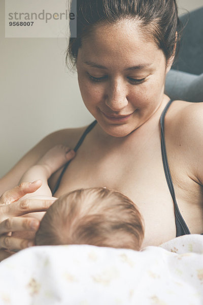 Porträt der lächelnden Mutter und des stillenden kleinen Babys