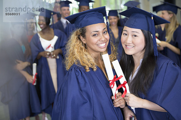 Porträt von lächelnden Studenten mit Diplomen auf dem Flur