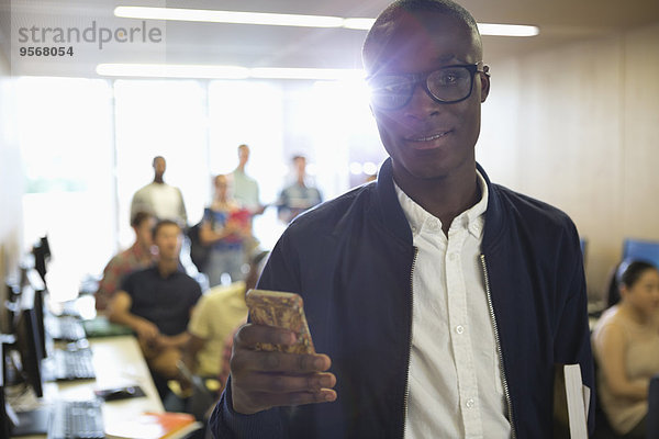 Portrait eines Studenten mit Smartphone im Klassenzimmer