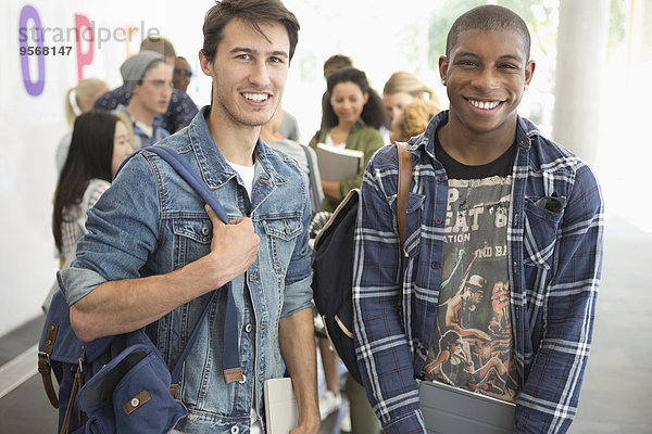 Zwei männliche Schüler lächeln vor der Kamera mit anderen Schülern im Hintergrund