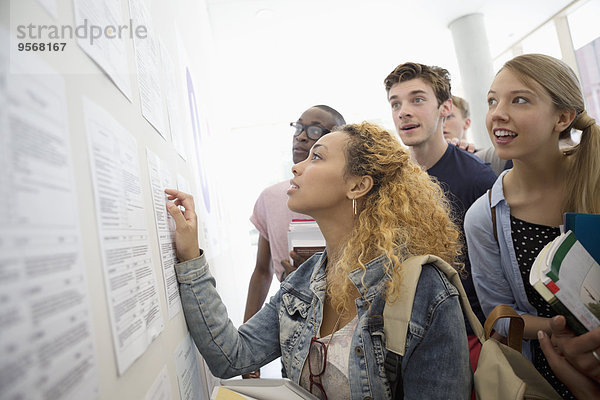 Gruppe von Schülern  die an der Informationstafel sitzen und Bücher in der Schule aufbewahren.