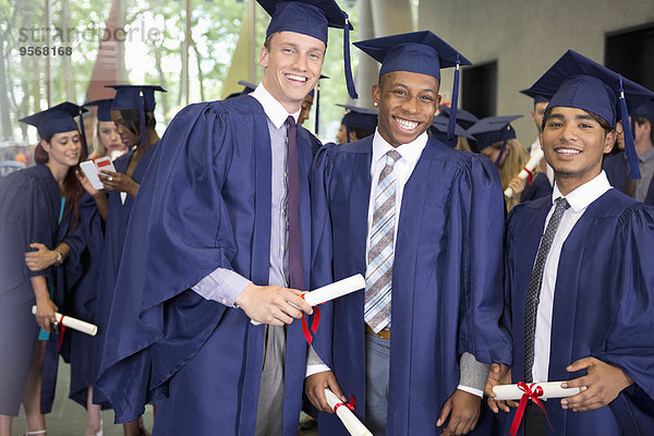Porträt von drei lächelnden männlichen Studenten in Diplom-Kleidern