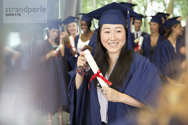 Porträt einer lächelnden Studentin im Diplom-Kleid