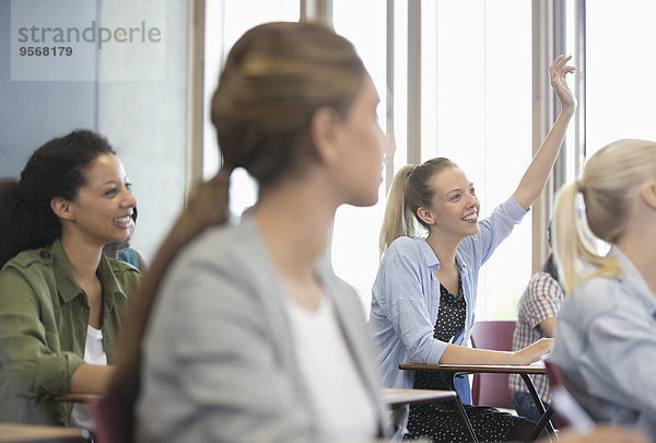 Blick auf lächelnde Schülerinnen am Schreibtisch im Klassenzimmer