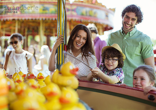 Eltern mit zwei Kindern beim Angelspiel im Vergnügungspark