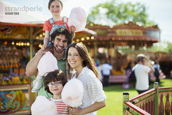 Porträt einer fröhlichen Familie mit rosa Zuckerwatte im Vergnügungspark