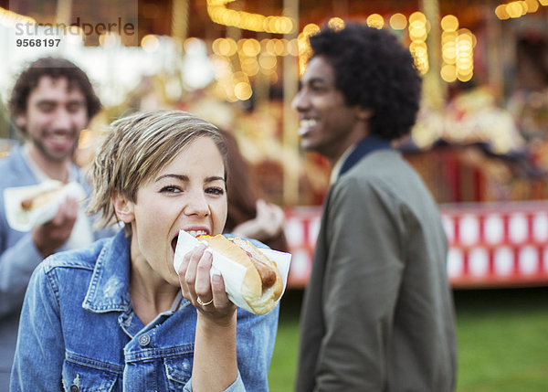 Drei junge Leute essen Hot Dogs im Vergnügungspark