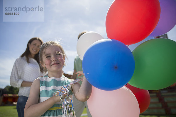 Junges Mädchen mit bunten Luftballons bei Sonnenschein