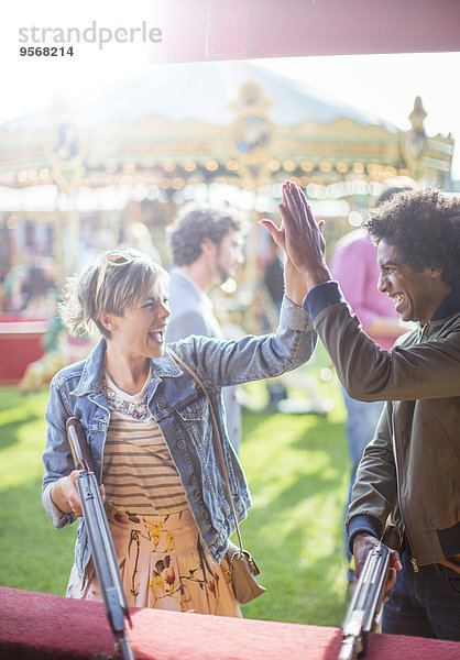 Junges Paar gibt High Five im Vergnügungspark