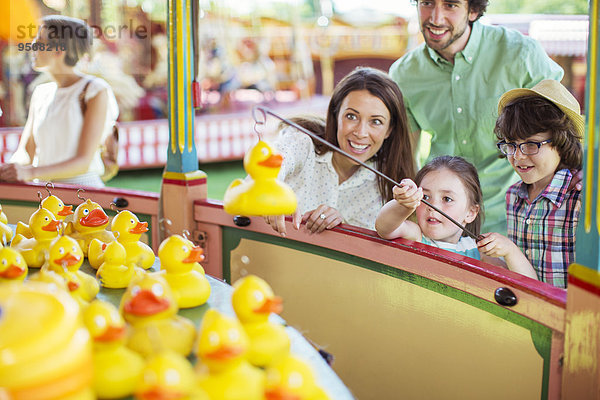 Eltern mit zwei Kindern beim Angelspiel im Vergnügungspark