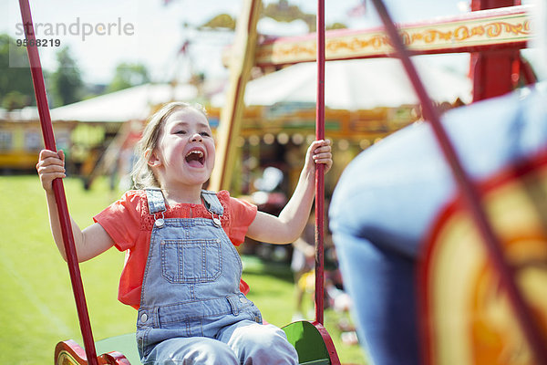 Fröhliches Mädchen lacht auf Karussell im Vergnügungspark
