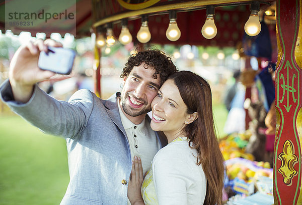 Lächelndes Paar nimmt Selfie im Vergnügungspark auf