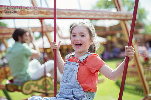 Fröhliches Mädchen lacht auf Karussell im Vergnügungspark