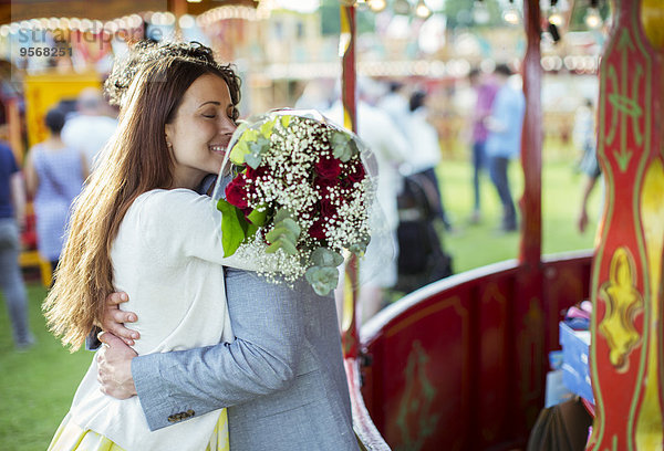Frau hält Blumenstrauß und umarmt seinen Freund im Vergnügungspark