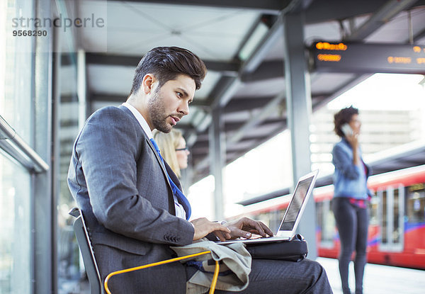 Geschäftsmann mit Laptop am Bahnhof