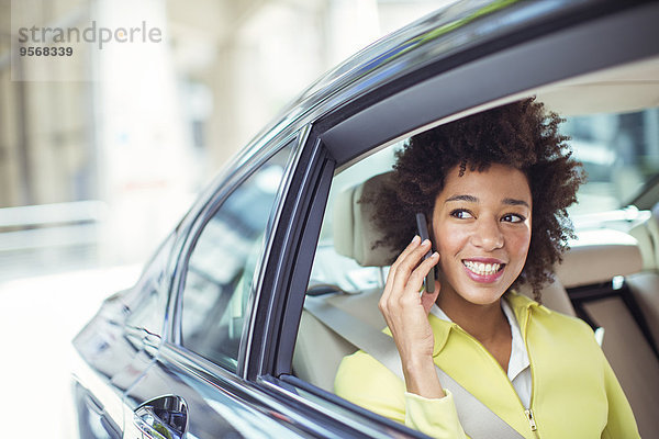 Geschäftsfrau beim Telefonieren auf dem Rücksitz des Autos