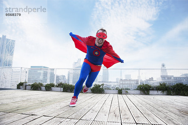 Superheldenlauf mit Umhang auf dem Stadtdach