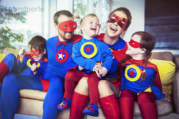 Superheldenfamilie lacht auf dem Sofa