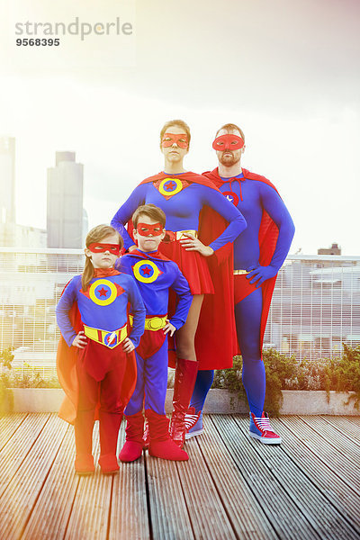 Superheldenfamilie steht auf dem Stadtdach