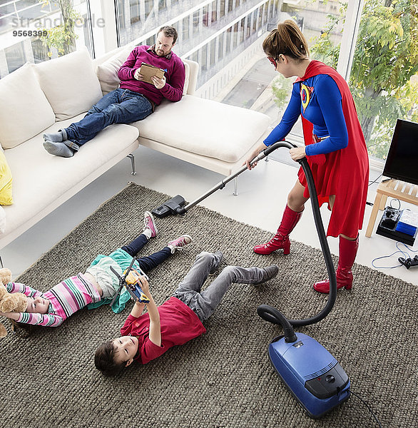 Superhelden saugen im Wohnzimmer um die Familie herum