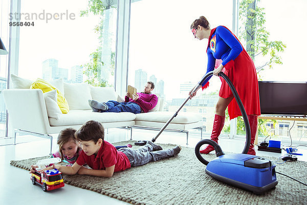 Superhelden saugen im Wohnzimmer um die Familie herum