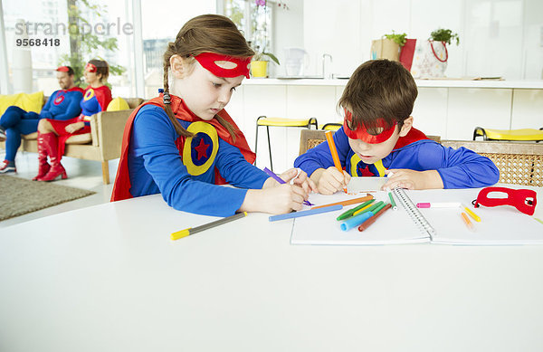 Superheldenkinder beim Zeichnen am Tisch