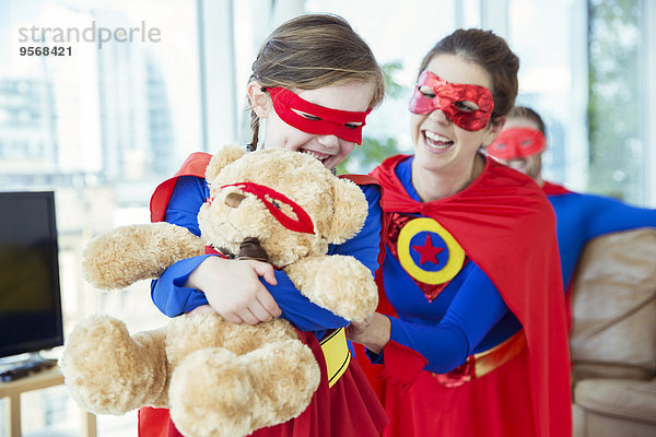 Superheldenmutter und -tochter spielen mit Teddybären