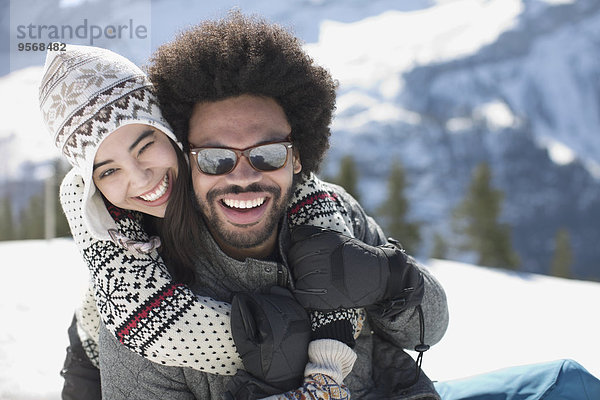 Porträt eines glücklichen Paares  das sich im Schnee umarmt.