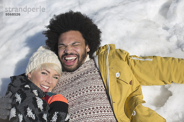 Porträt des glücklichen Paares im Schnee liegend