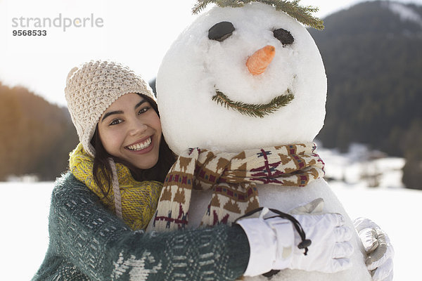 Porträt einer lächelnden Frau  die den Schneemann umarmt