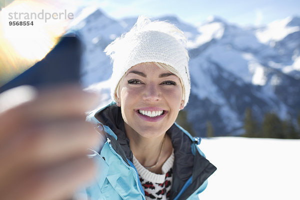 Lächelnde Frau  die Selfie im Schnee nimmt