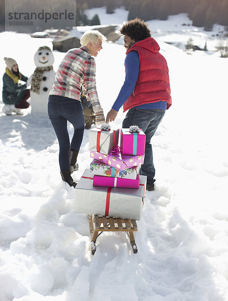 Paar Ziehschlitten mit Weihnachtsgeschenken im Schnee