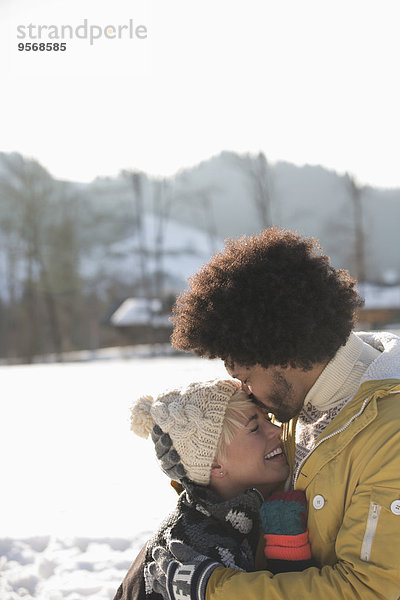 Mann küsst Frauenstirn im Schnee