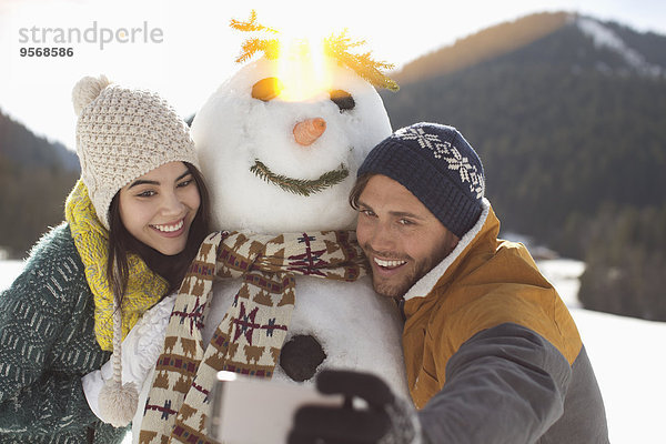 Pärchen nehmen Selfie mit Schneemann