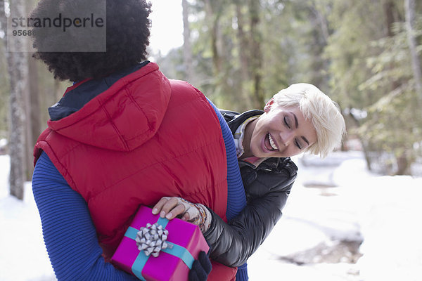 Frau schaut auf Weihnachtsgeschenk hinter dem Rücken des Mannes