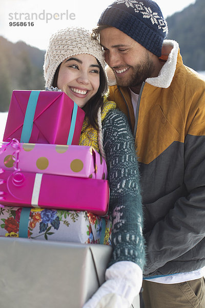 Paar mit Weihnachtsgeschenken im Schnee