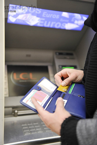 Junge Frau zieht Geld von einem Geldautomaten ab