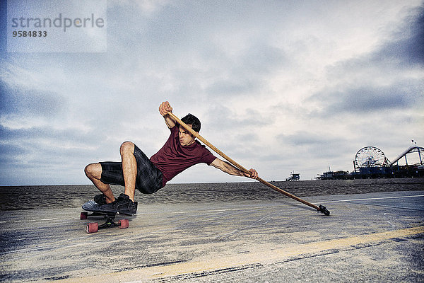 Europäer Mann Strand Stange Paddel Skateboarding