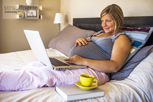 benutzen Europäer Frau Notebook Bett Schwangerschaft