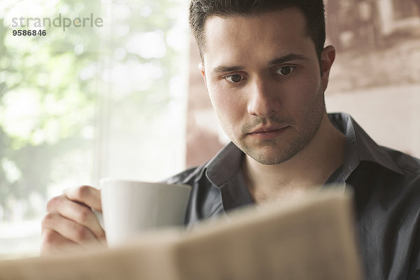 Mann Tasse trinken Kaffee Zeitung vorlesen