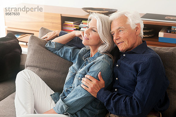 Porträt eines liebenden älteren Paares  das Seite an Seite auf der Couch sitzt.